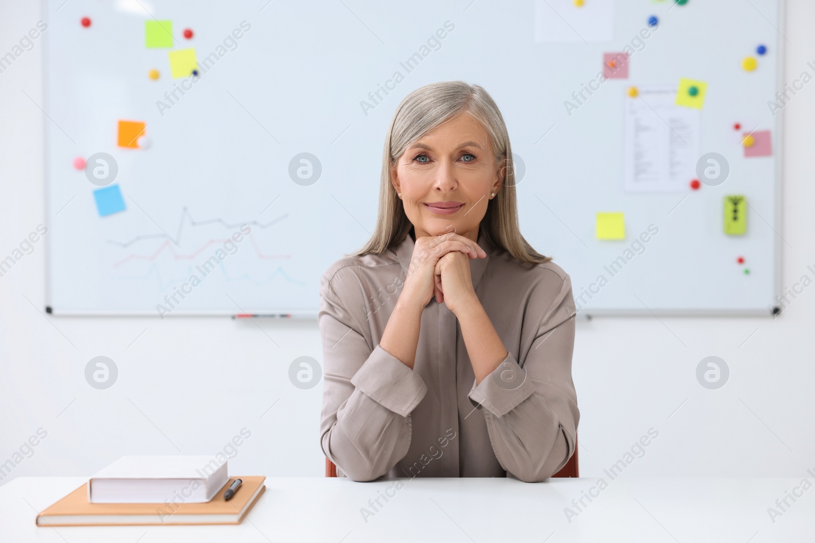 Photo of Portrait of professor sitting at desk in classroom