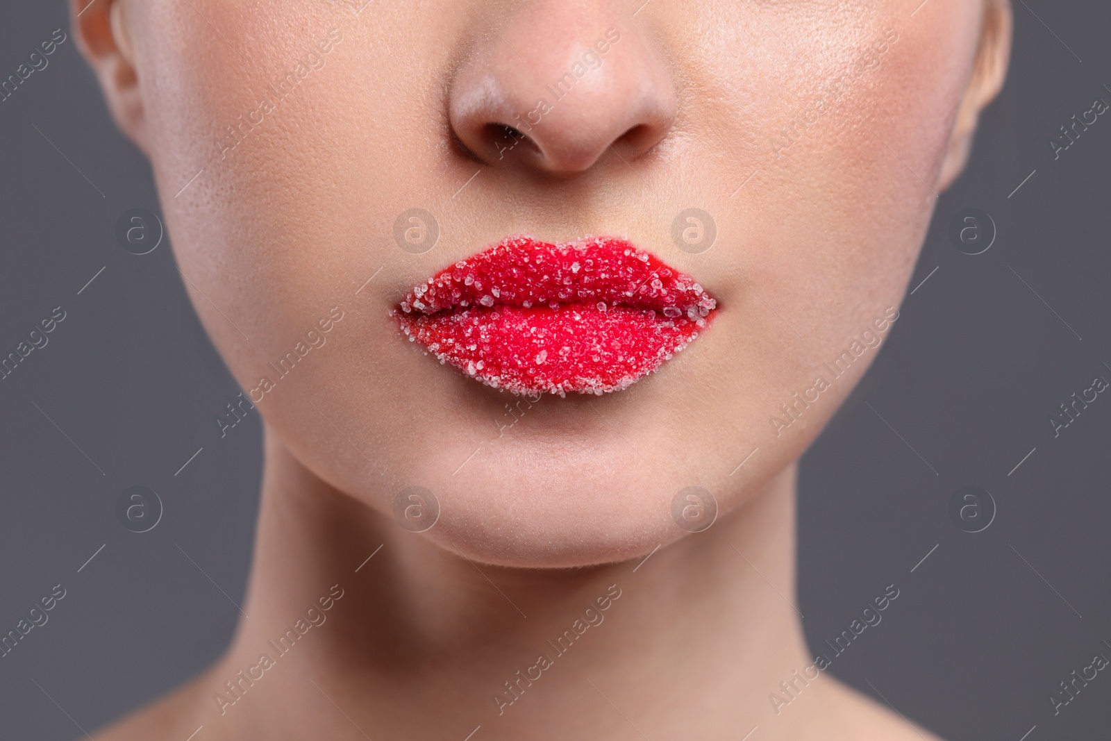 Photo of Woman with beautiful lips covered in sugar on grey background, closeup