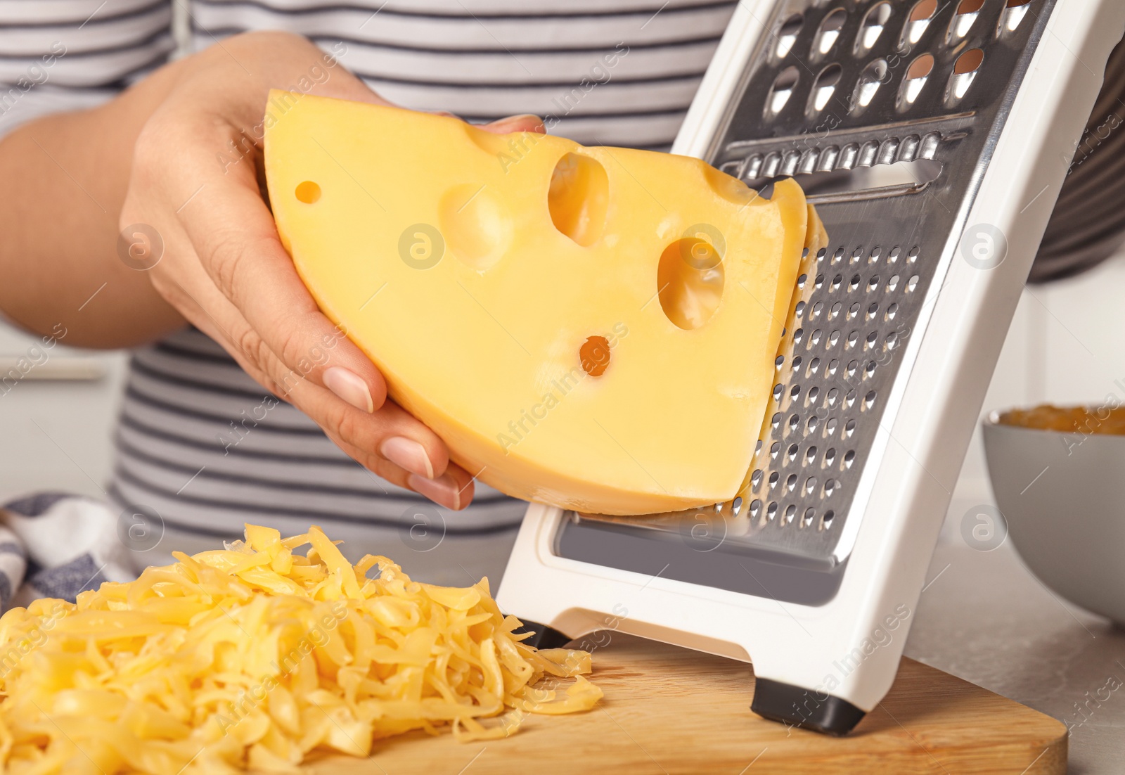 Photo of Woman grating fresh cheese at table, closeup