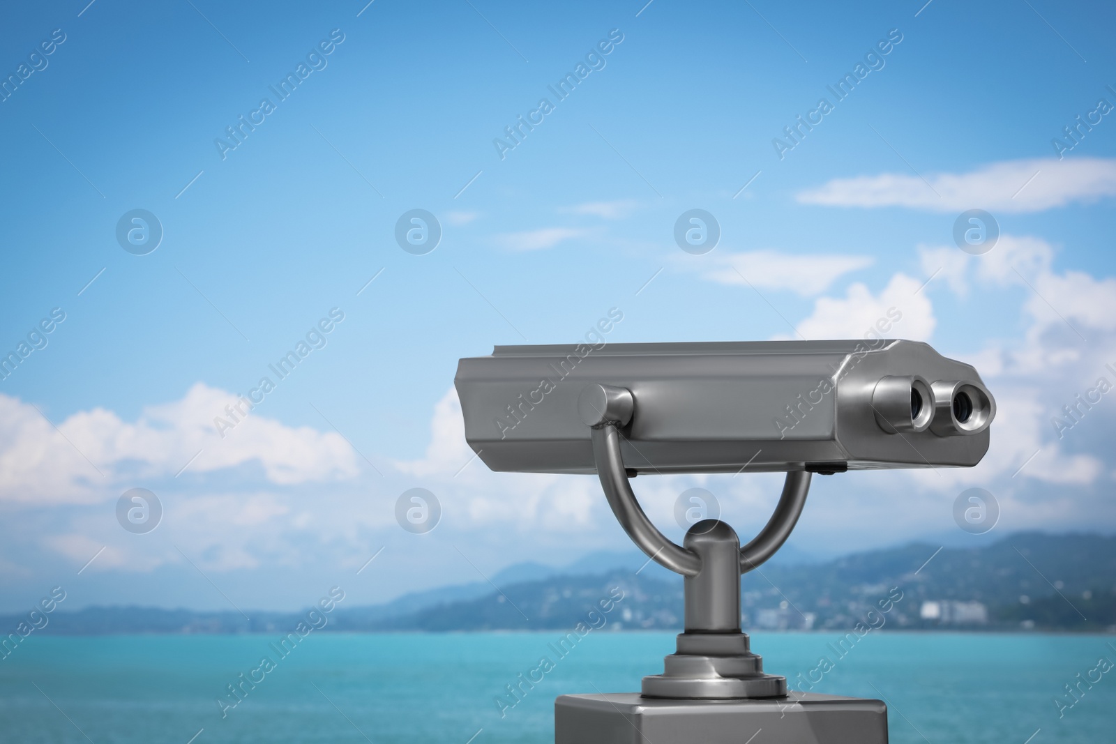 Photo of Metal tower viewer installed near sea, space for text. Mounted binoculars