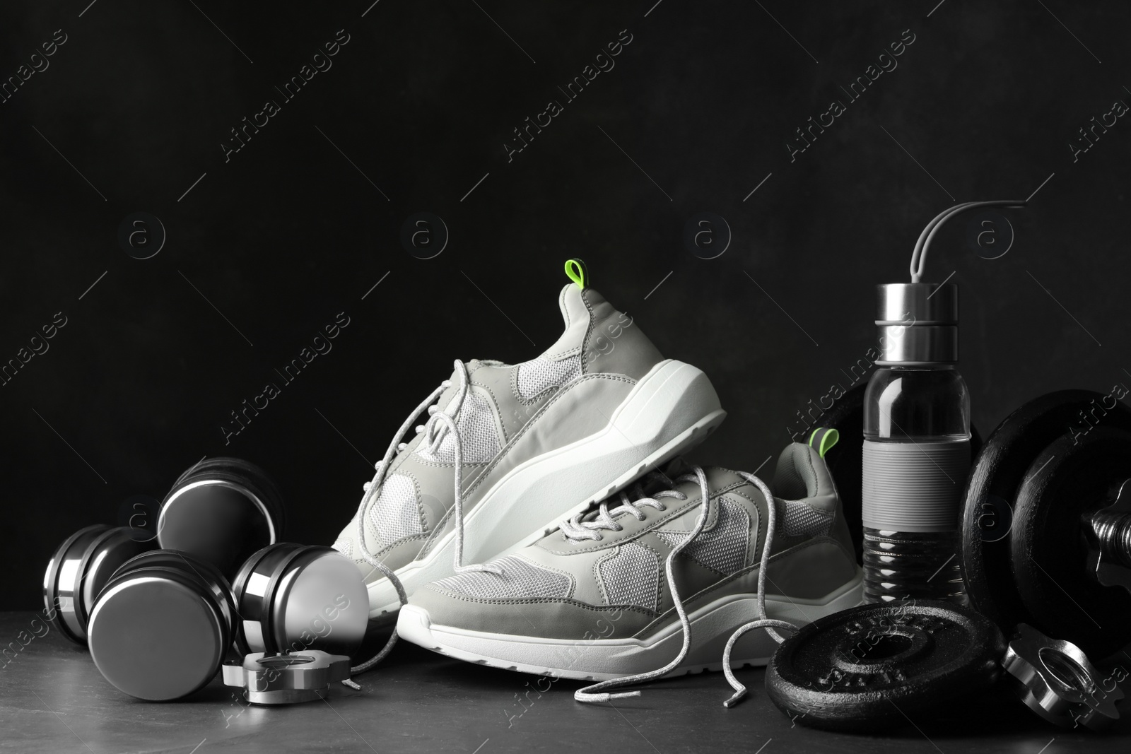 Gym equipment and accessories on stone floor against dark background Photo of Gym equipment and accessories on stone floor against dark background