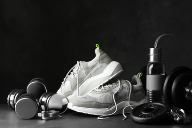 Photo of Gym equipment and accessories on stone floor against dark background