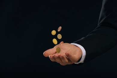 Image of Man and coins falling into his hand on black background, closeup