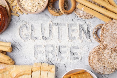Photo of Different products and phrase Gluten free written with flour on light grey table, flat lay