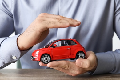 Male insurance agent holding toy car, closeup