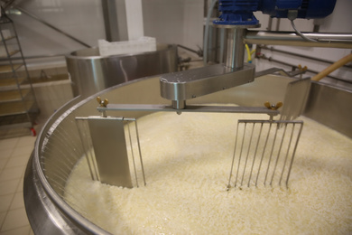 Adding water to curd and whey in tank at cheese factory