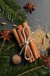 Different spices, nut and fir branches on gray table, flat lay