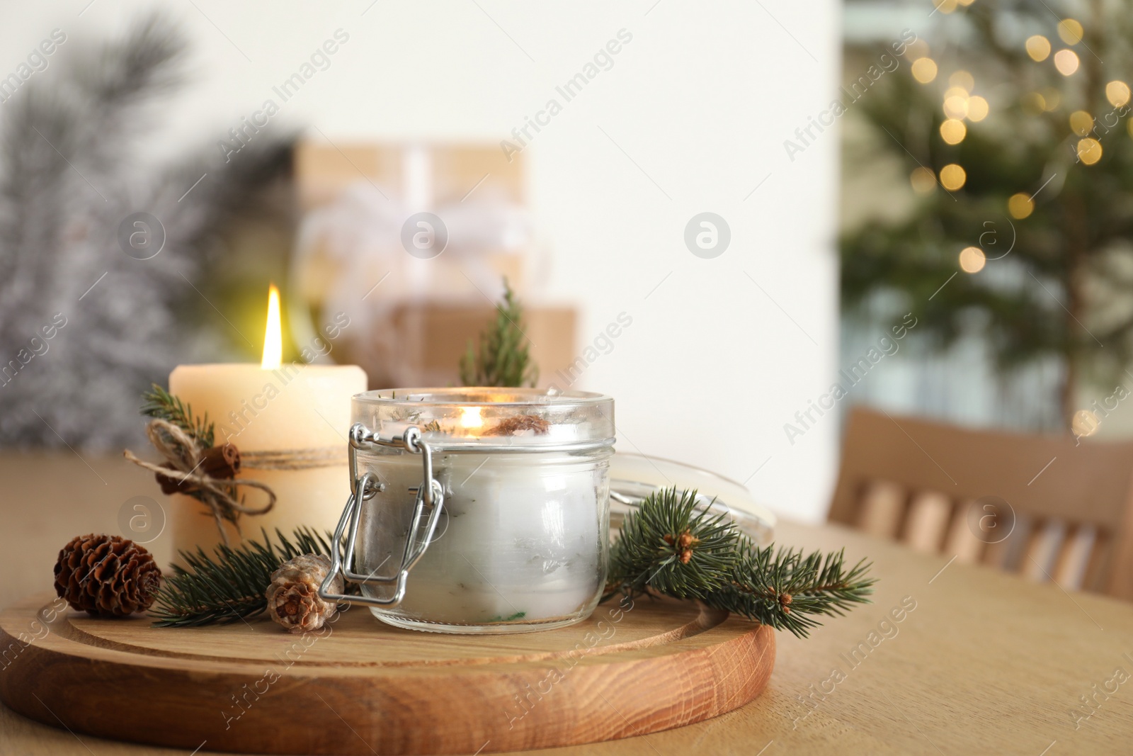 Photo of Burning scented conifer candles and Christmas decor on wooden table indoors. Space for text