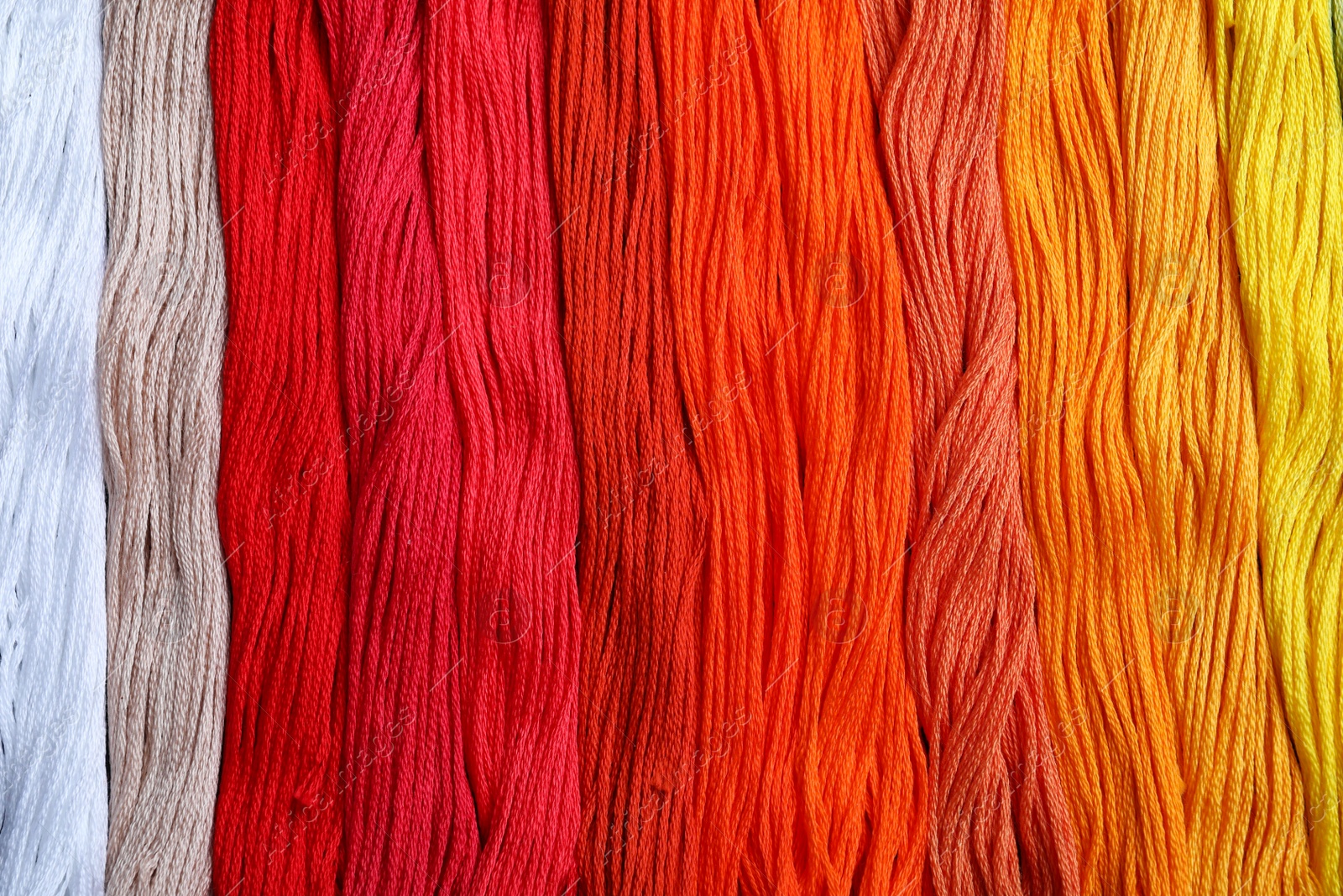 Photo of Different colorful embroidery threads as background, top view