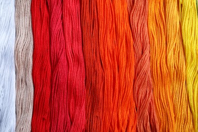 Different colorful embroidery threads as background, top view