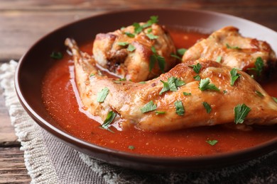 Tasty cooked rabbit meat with sauce and parsley on table, closeup