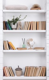 Photo of Collection of books and decor elements on shelves indoors