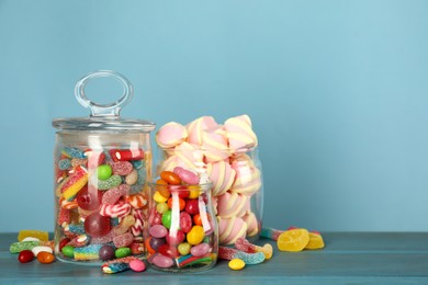 Photo of Jars with different delicious candies on turquoise wooden table, space for text