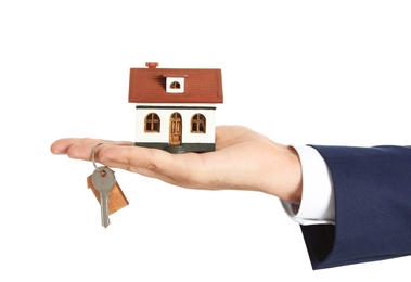 Real estate agent holding house model and key on white background, closeup