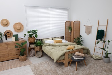 Photo of Stylish bedroom with comfortable bed and beautiful green houseplants. Interior design