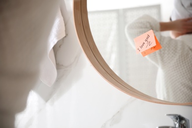 Photo of Sticky note with handwritten text I Love You on mirror in bathroom. Romantic message