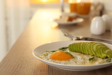 Photo of Tasty breakfast with fried egg and avocado on wooden table