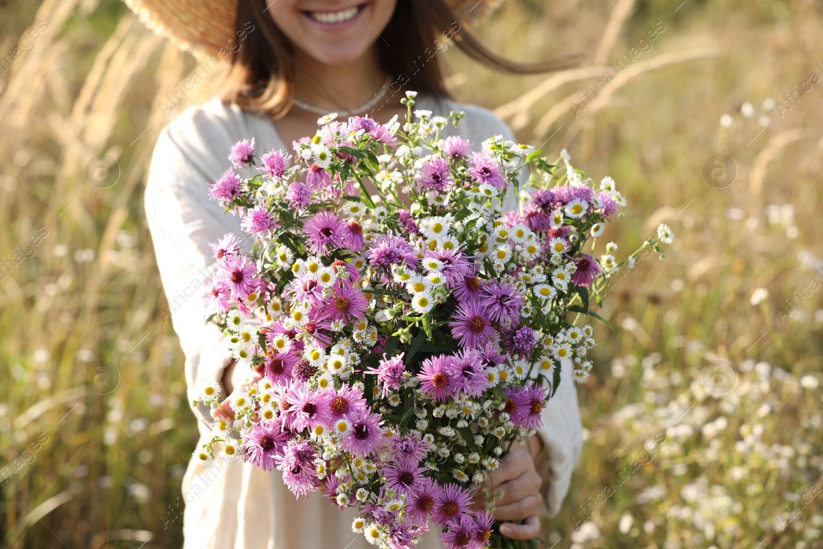 Photo of Woman holding bouquet of beautiful wild flowers outdoors, closeup