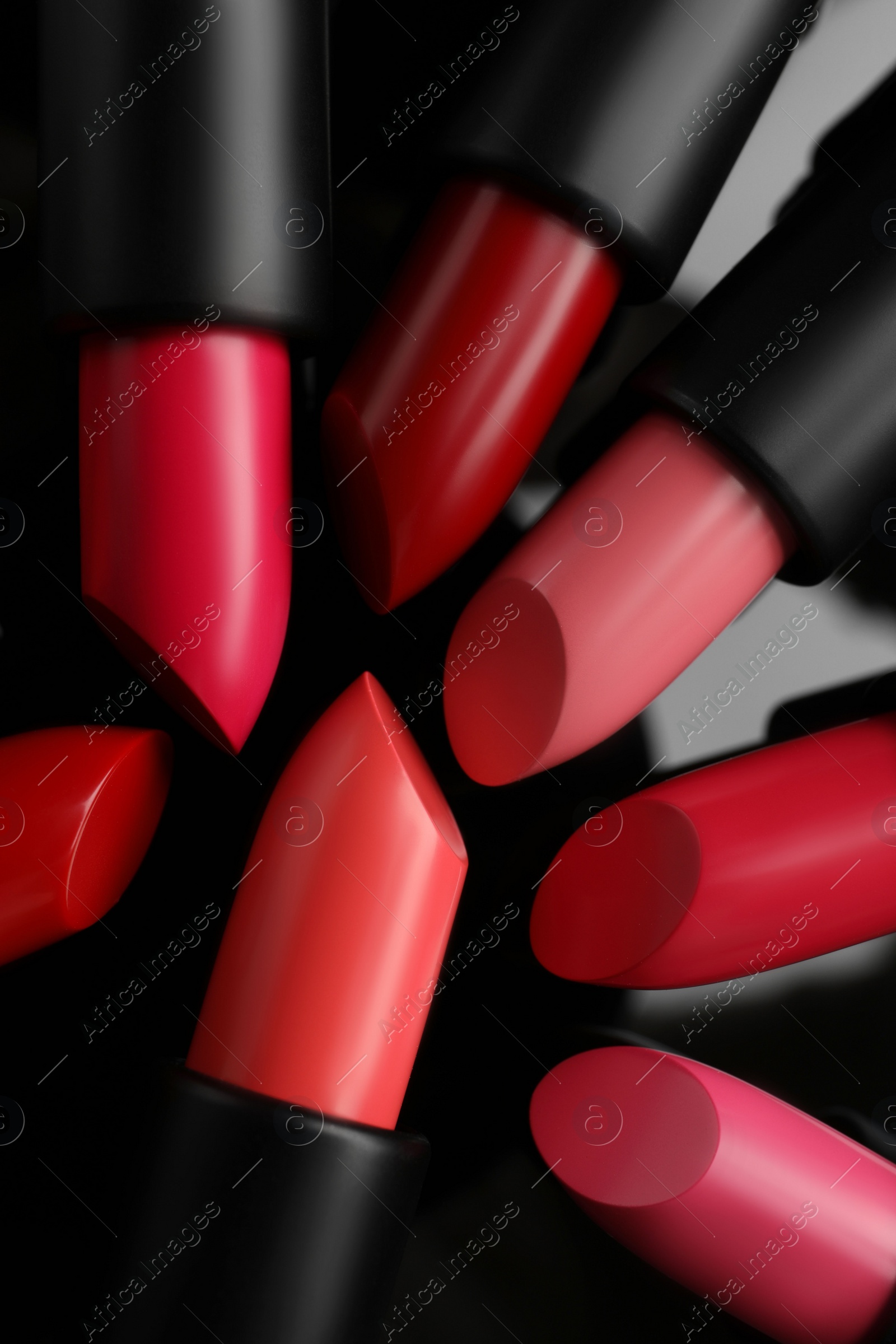 Photo of Many bright lipsticks on black glass surface, flat lay