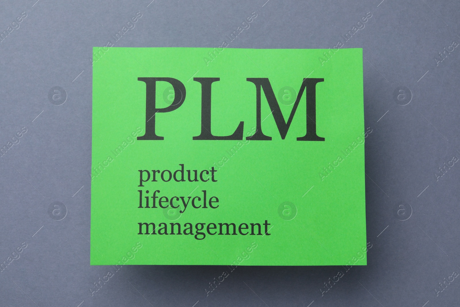 Photo of Green paper with abbreviation PLM (Product Lifecycle Management) on grey background, top view