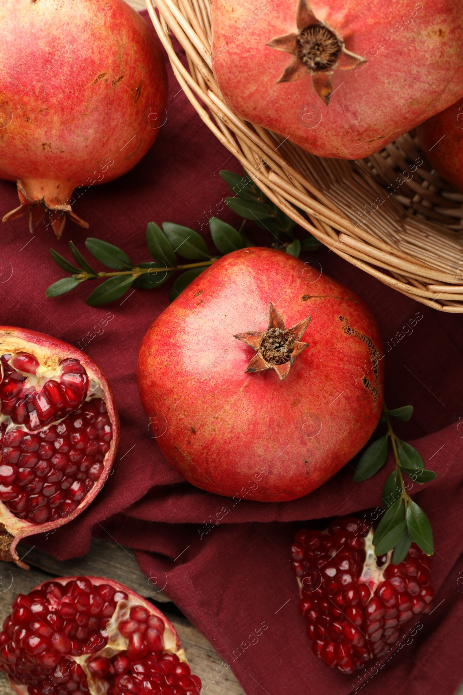 Photo of Fresh pomegranates and green leaves on table, top view