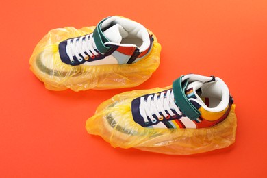 Sneakers in shoe covers on orange background, above view