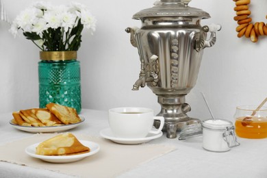 Photo of Vintage samovar, cuphot drink and snacks served on table. Traditional Russian tea ceremony