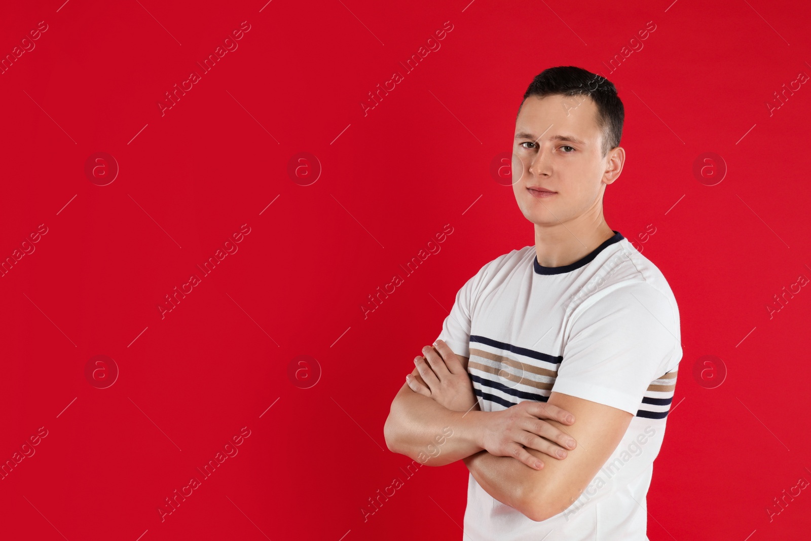 Photo of Handsome young man posing on red background. Space for text