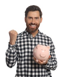 Photo of Happy man with ceramic piggy bank on white background