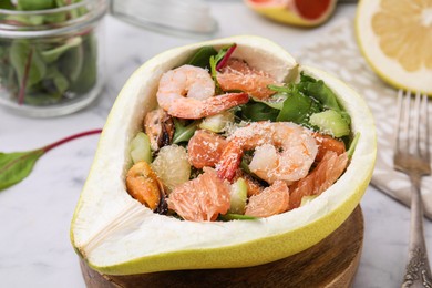 Photo of Delicious pomelo salad with shrimps in half of fruit on table, closeup