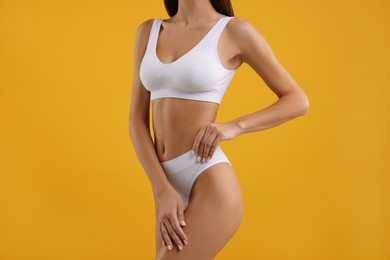 Young woman in stylish white bikini on orange background, closeup