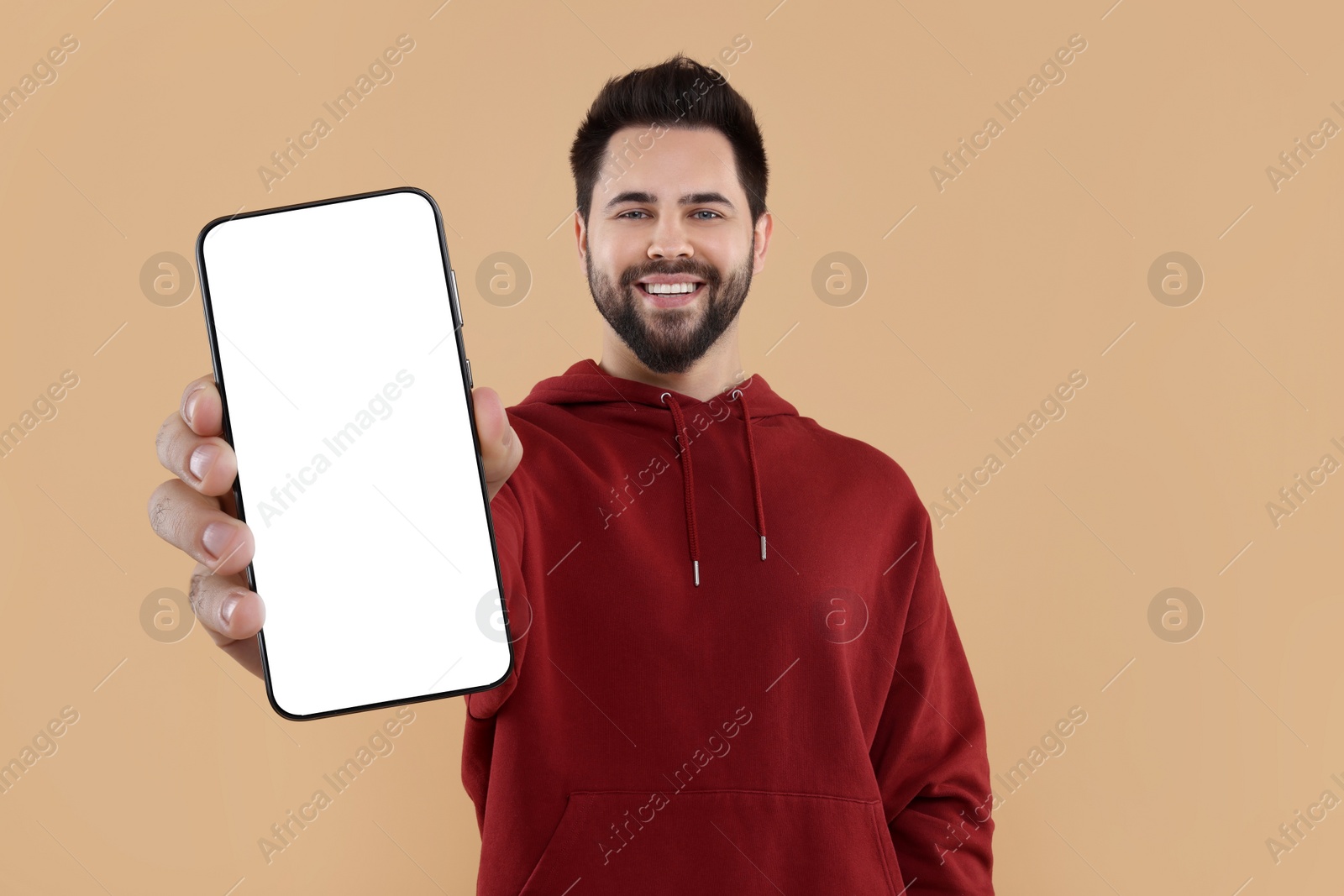 Image of Happy man holding smartphone with empty screen on beige background