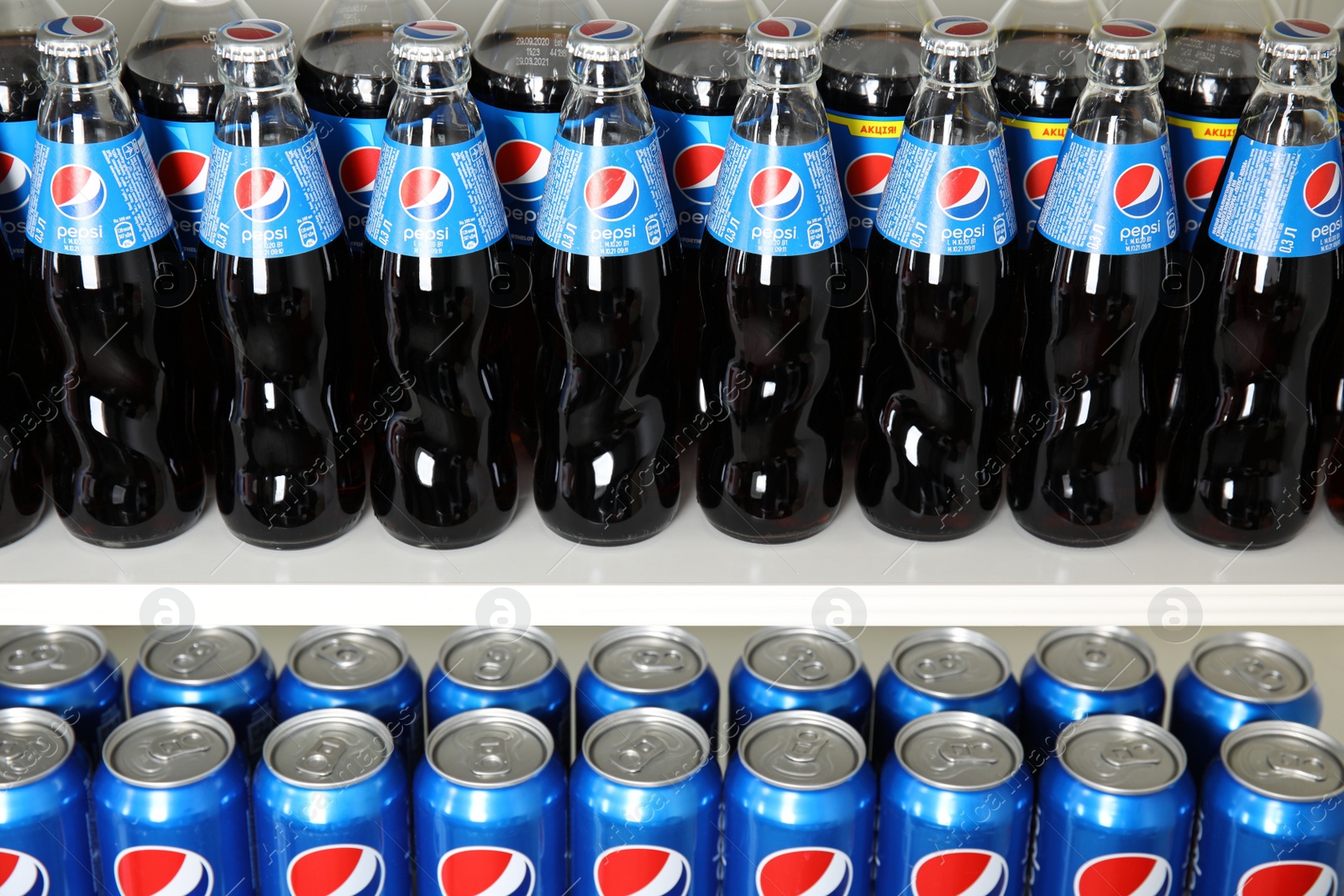 Photo of MYKOLAIV, UKRAINE - FEBRUARY 10, 2021: Cans and bottles of Pepsi on white shelves