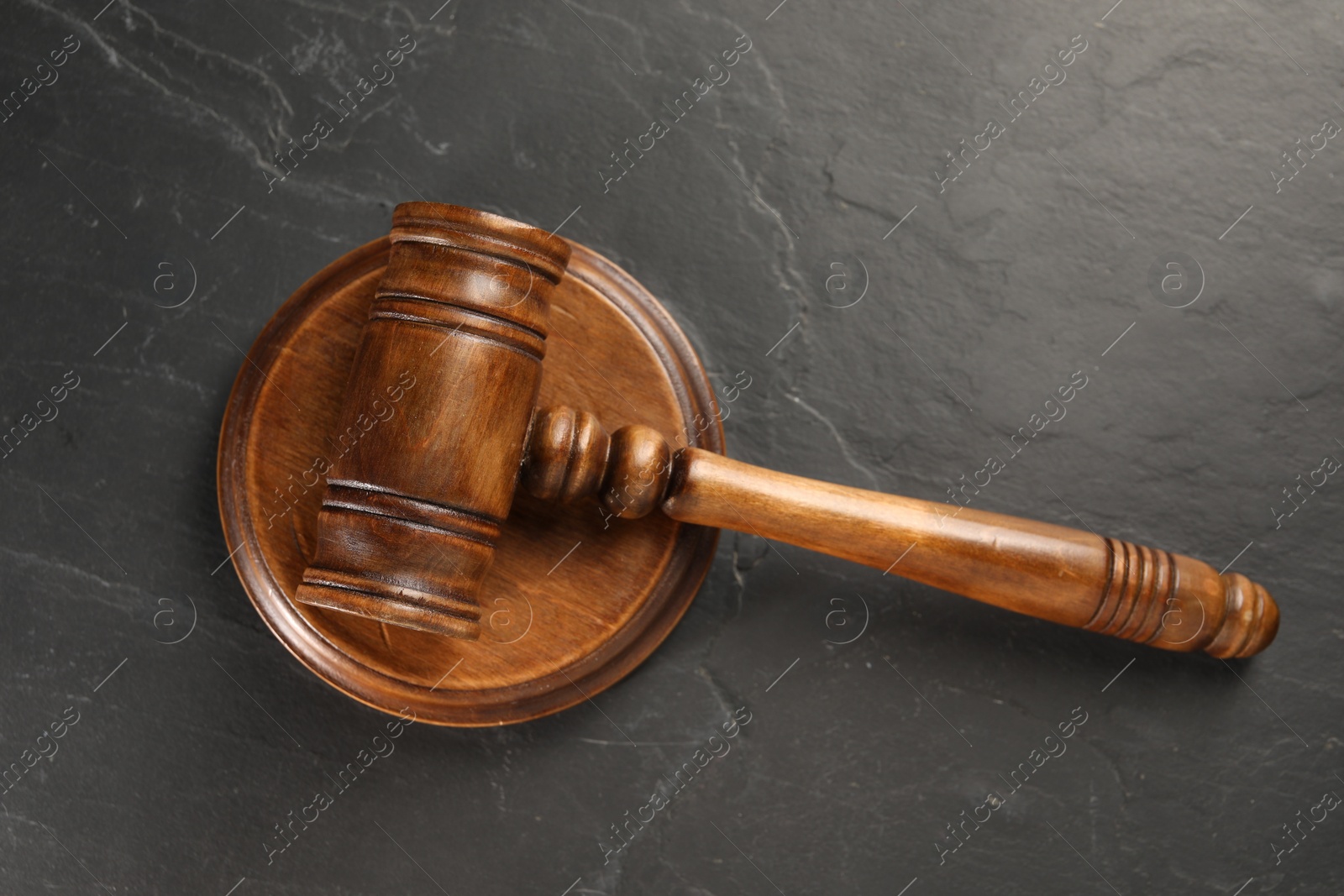 Photo of Wooden gavel on dark textured table, top view