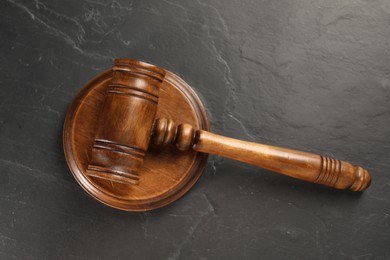 Photo of Wooden gavel on dark textured table, top view