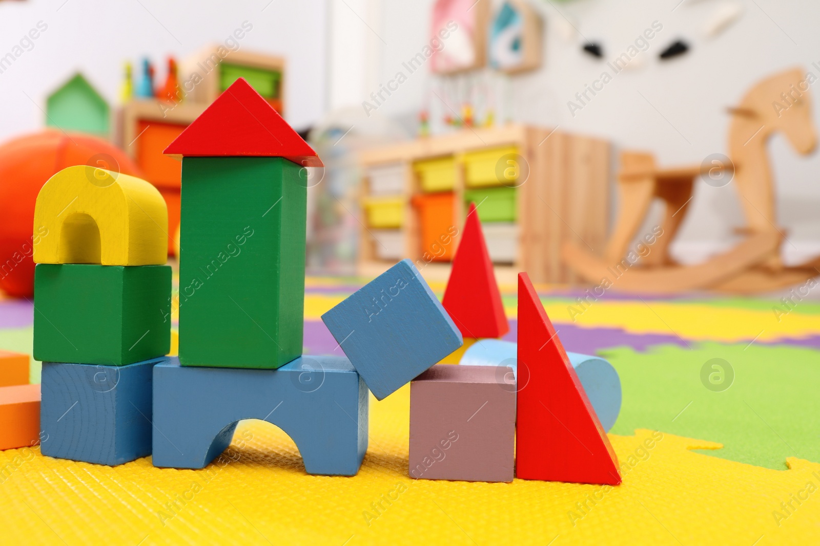 Photo of Wooden castle made of colorful blocks on carpet in playroom. Interior design