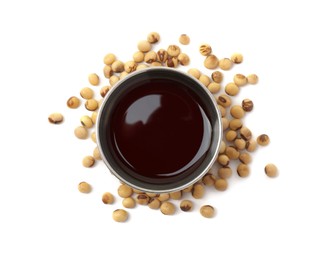 Photo of Tasty soy sauce in bowl and soybeans isolated on white, top view