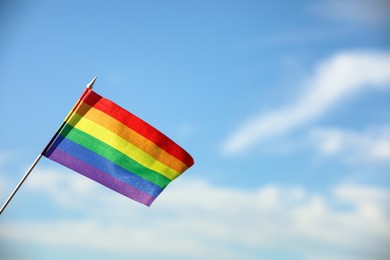 Photo of Bright LGBT flag against blue sky with clouds, space for text