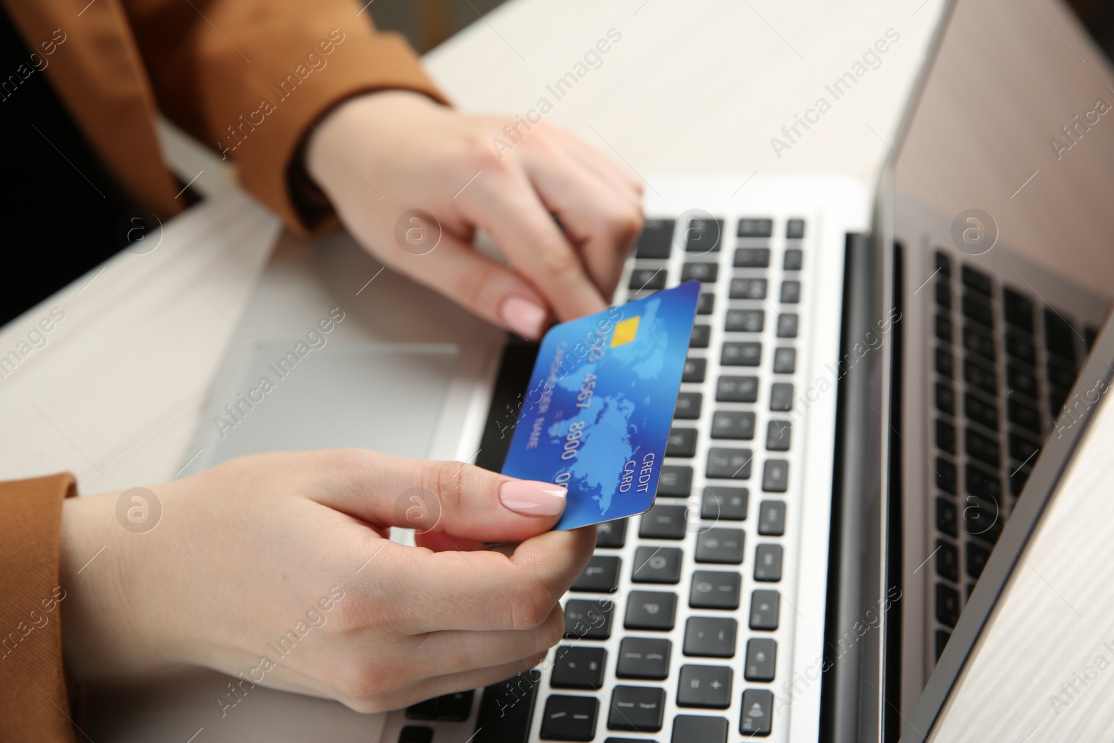 Photo of Online payment. Woman with credit card using laptop at white table, closeup