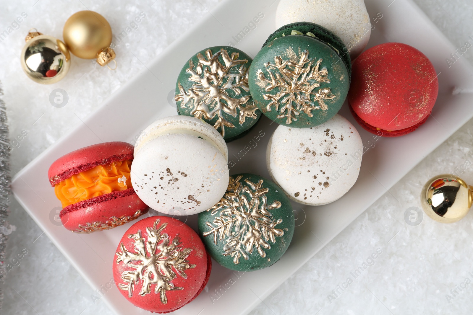 Photo of Beautifully decorated Christmas macarons and festive decor on snow, flat lay