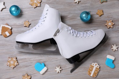 Pair of ice skates, Christmas cookies and balls on wooden background, flat lay