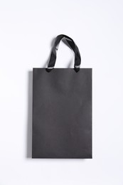 Photo of One black paper shopping bag on white background, top view
