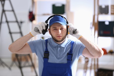 Photo of Worker wearing safety headphones indoors. Hearing protection device