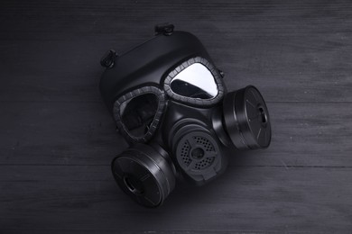 Photo of One gas mask on black wooden background, top view