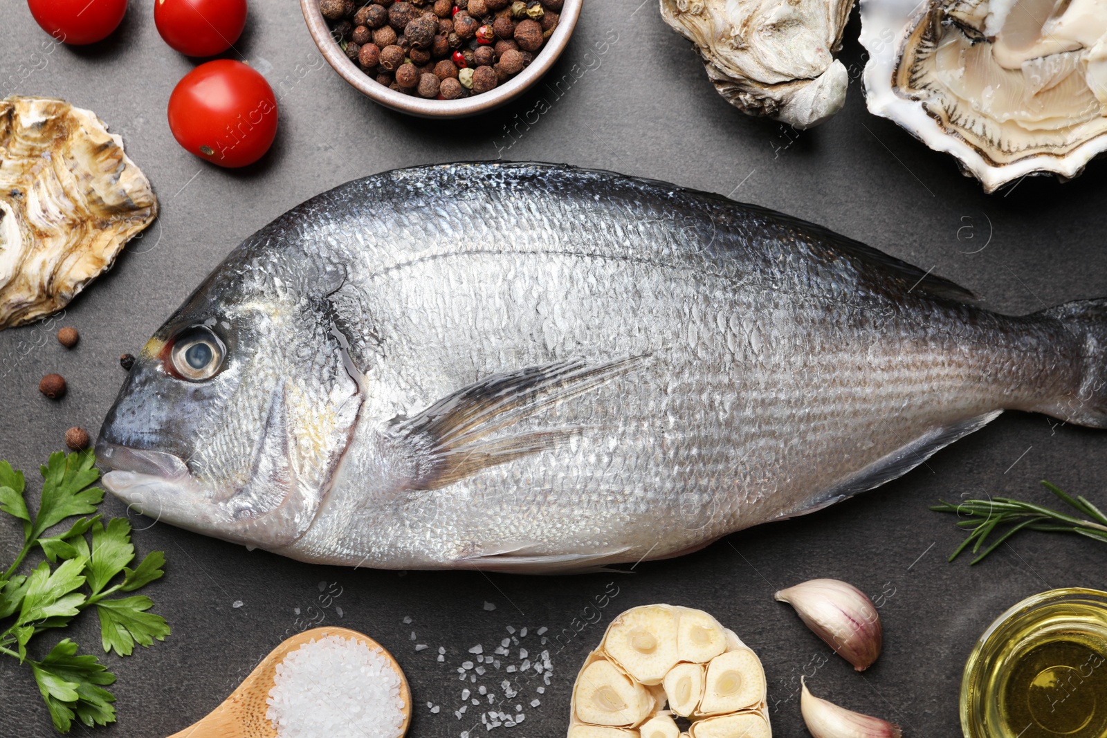 Photo of Fresh raw dorado fish, oysters and spices on grey table, flat lay