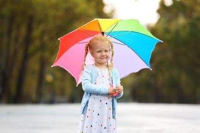 Cute little girl with bright umbrella on street