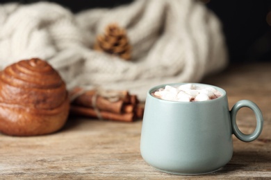 Delicious cocoa drink with marshmallows in cup on wooden table, space for text