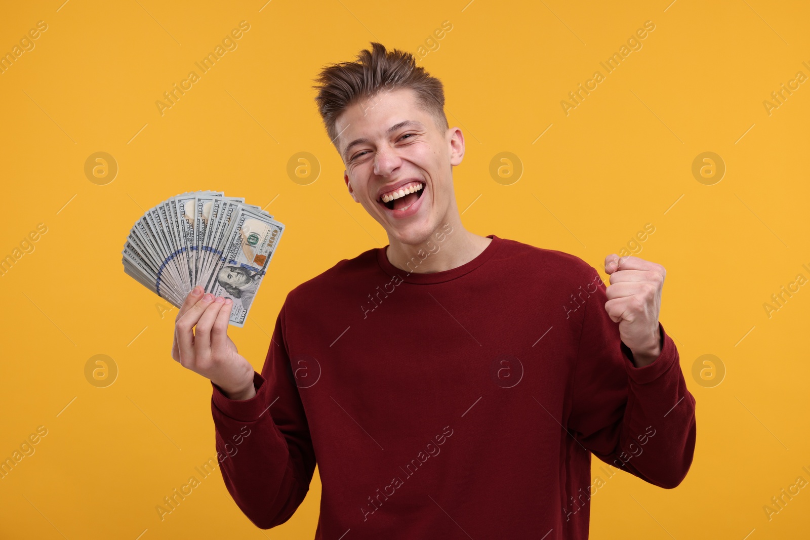 Photo of Happy man with dollar banknotes on yellow background