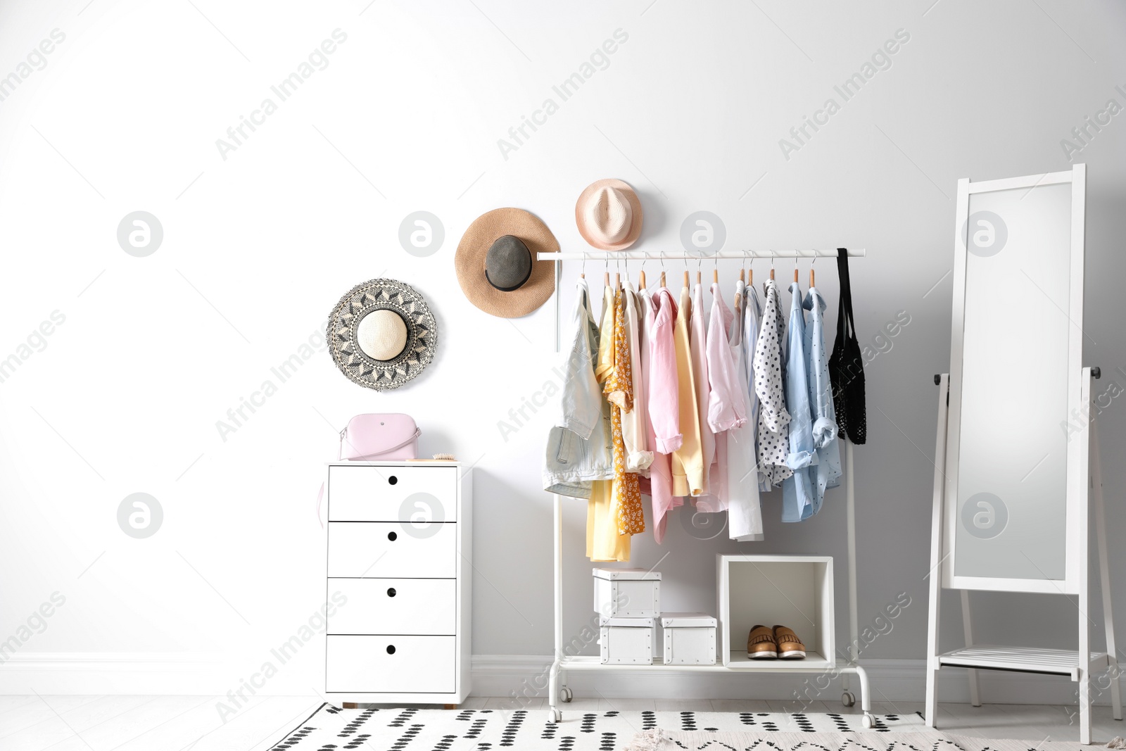 Photo of Rack with stylish women's clothes and mirror indoors. Interior design