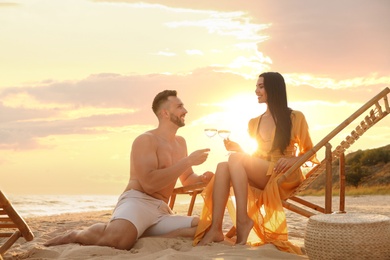 Photo of Romantic couple drinking wine together on beach at sunset